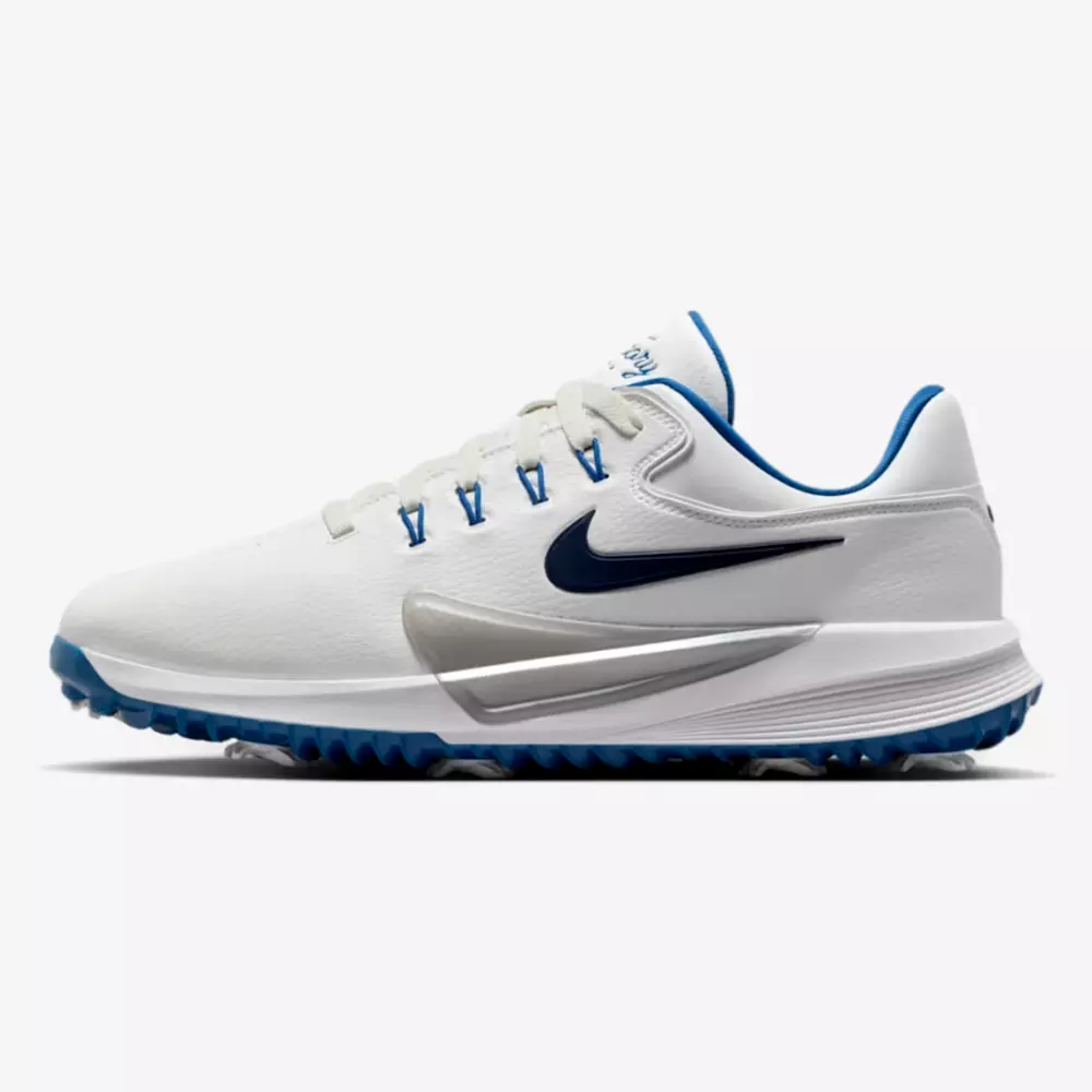 A white athletic shoe with blue accents, a blue Nike swoosh logo, blue lace eyelets, and blue outsole tread. With its low-cut design, it stands out as one of the best golf shoes 2026 against a plain white background.