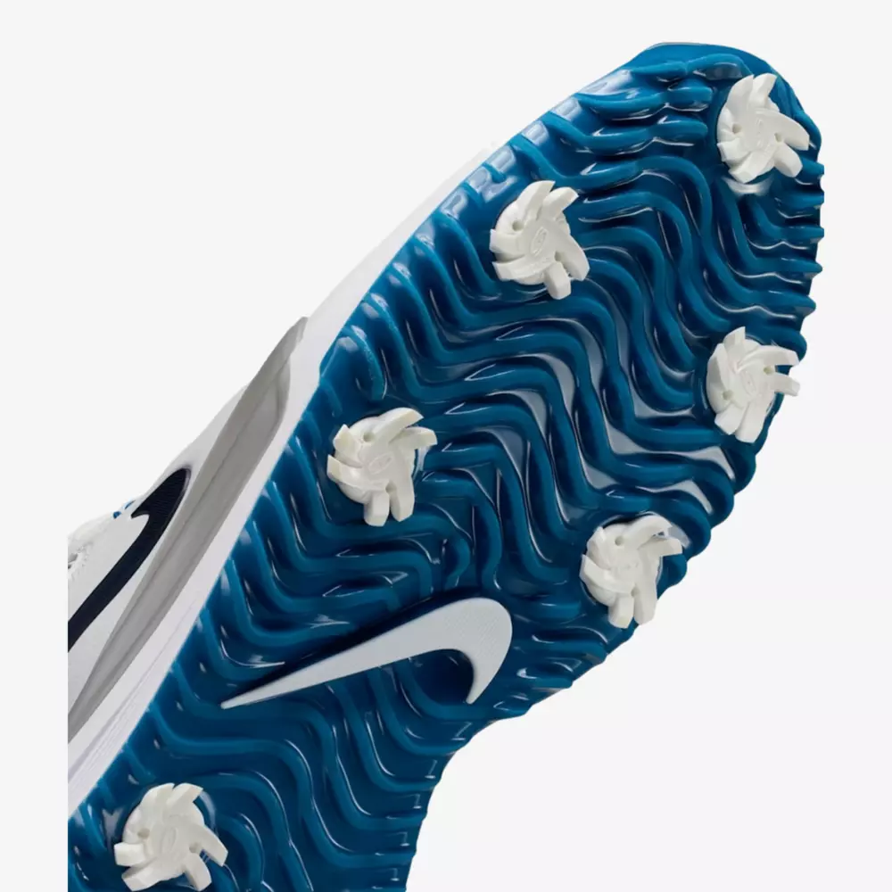 Close-up view of the blue sole of one of the best golf shoes 2026, featuring white cleats, a white Nike logo, wavy tread patterns, and six visible spikes for superior traction.