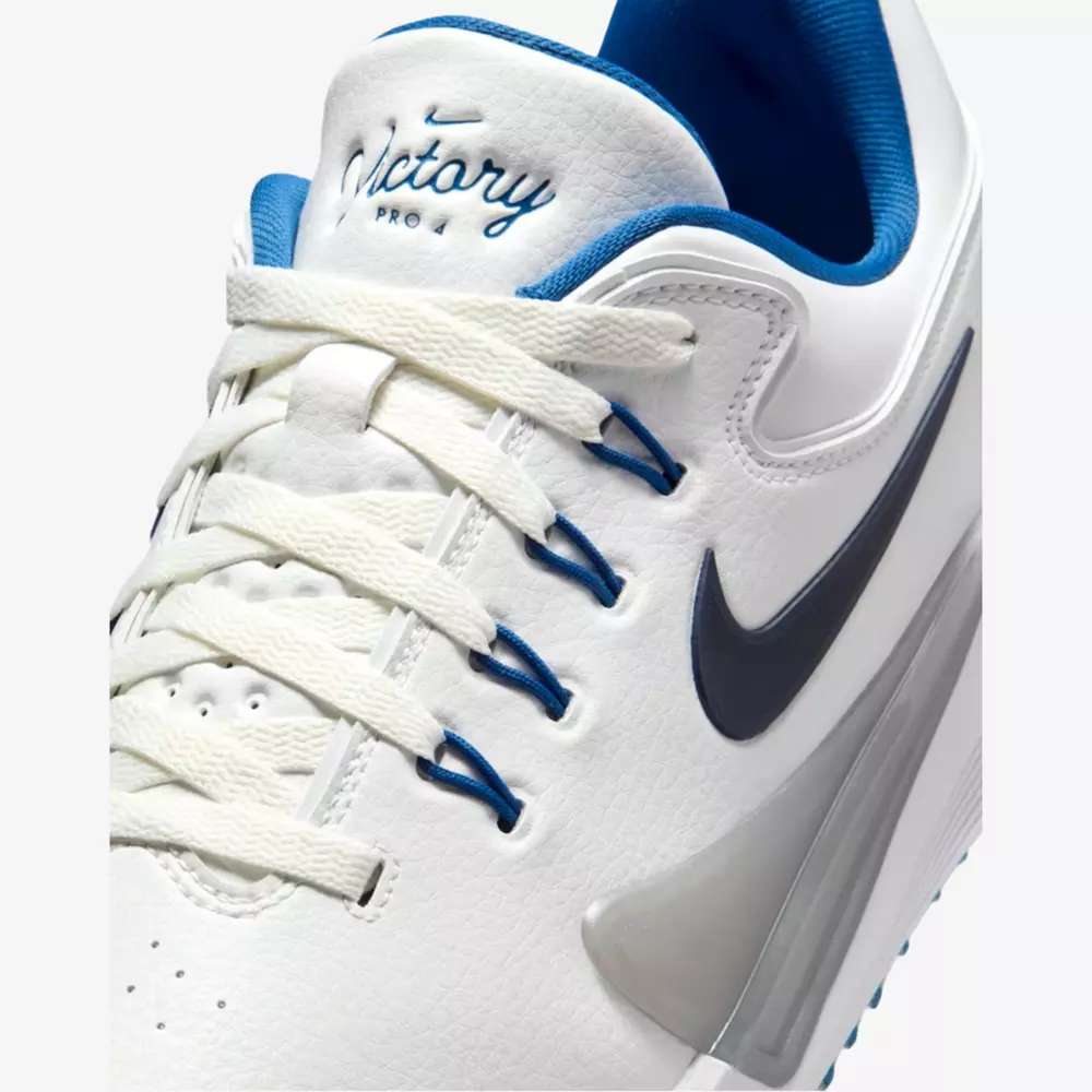 Close-up of a white Nike sneaker with blue accents, white laces, and a black Nike swoosh&mdash;perfect for those seeking the best golf shoes 2026. The tongue features 