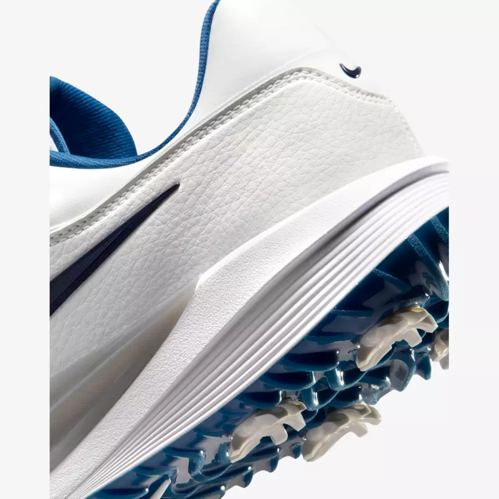 Close-up of a white athletic shoe with blue accents and spiked sole, highlighting textured leather material and detailed tread pattern&mdash;an ideal pick among the best golf shoes 2026 has to offer.