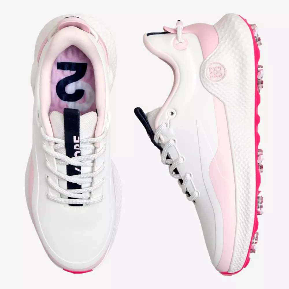 A pair of white golf shoes with pink accents, shown from the top and side. Featuring white laces, a dark navy tongue, and a textured sole with pink spikes&mdash;these are contenders for the best golf shoes 2026.