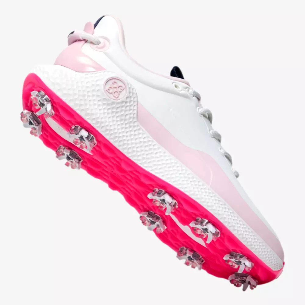 A white golf shoe with light pink accents and a bright pink spiked sole, shown from a low angle highlighting the tread and side design&mdash;an eye-catching contender for the best golf shoes 2026.