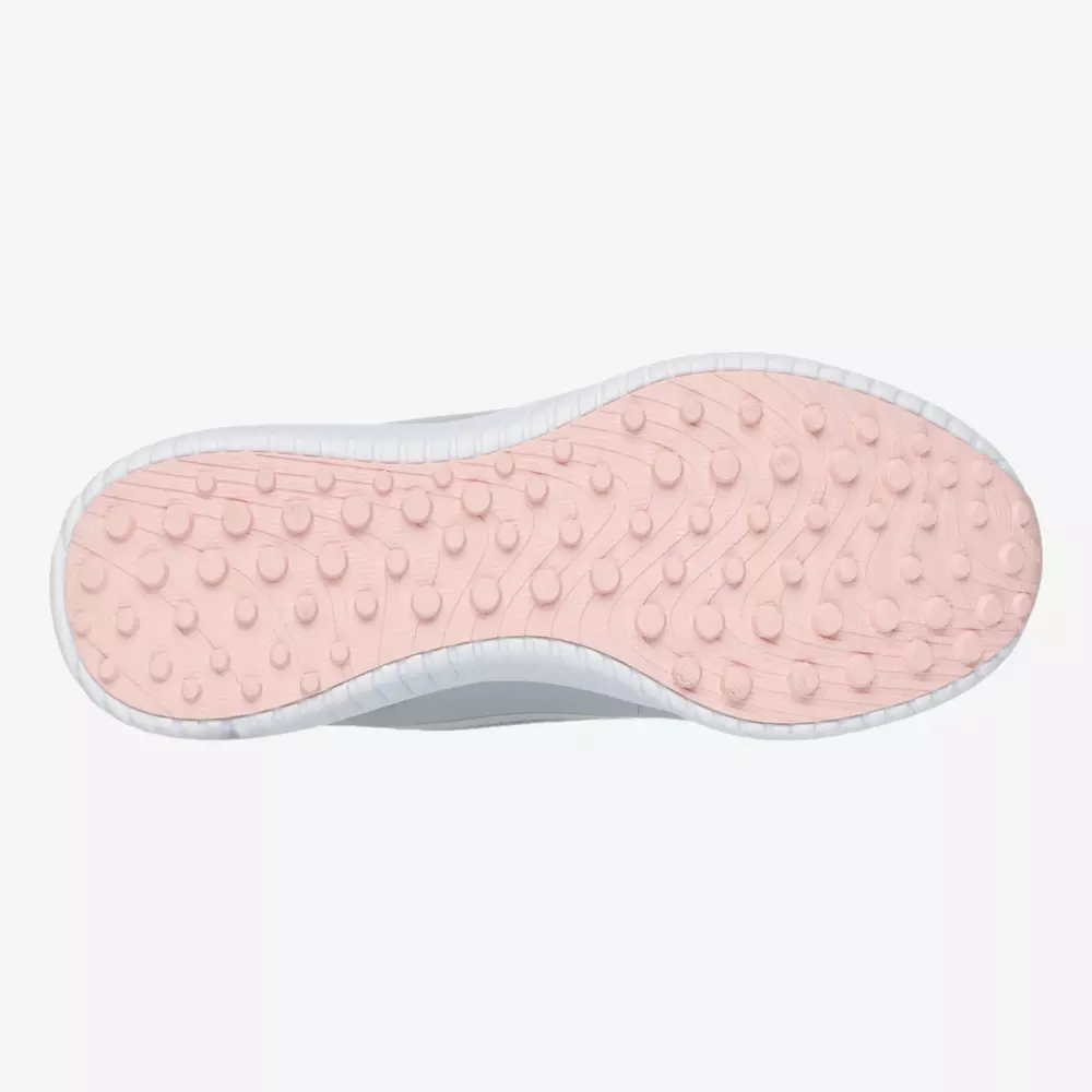 A shoe sole from the best women's golf shoes 2026, featuring a light pink color and raised circular traction patterns, is viewed from the bottom against a white background. The edge of the sole is crisp white.