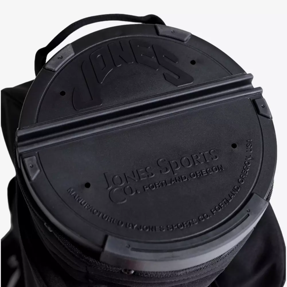 Close-up of a black circular cover with embossed text JONES and Jones Sports Co. Portland, Oregon on a bag, exemplifying the sturdy construction found in the best golf bags 2026, with a convenient top handle.