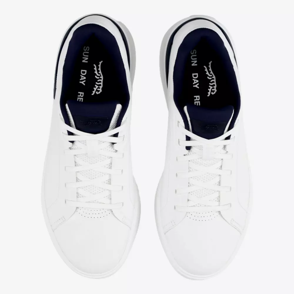 Top view of a pair of white sneakers with white laces and dark navy inner lining, reminiscent of the best golf shoes 2026. The insoles read SUN DAY RE in white, possibly part of a longer phrase. The shoes are placed side by side.