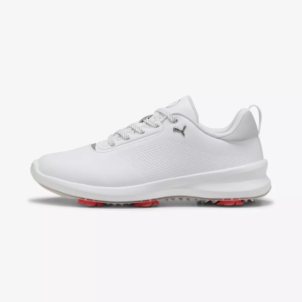 A white athletic sneaker with a mesh-textured side, white laces, subtle Puma logo, and a white sole with small pink traction studs underneath&mdash;an ideal contender for the best golf shoes 2026&mdash;shown in side profile on a plain background.
