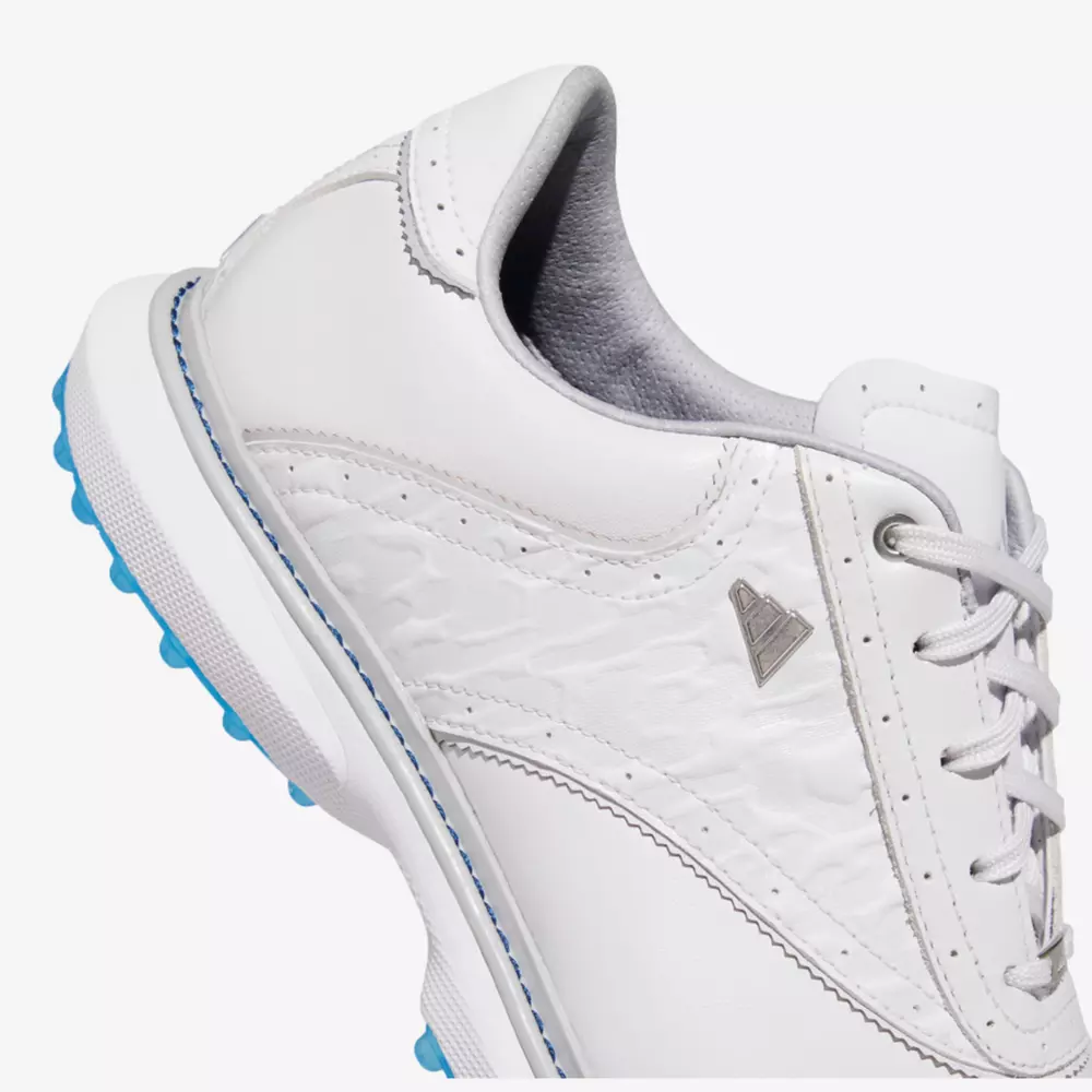 Close-up of a white sneaker with light blue accents, textured side panel, white laces, and a silver triangular logo on the side&mdash;styled like the best Jordan golf shoes&mdash;shown on a plain background.