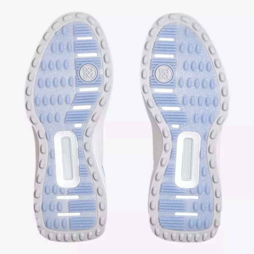 The image shows the outsoles of a pair of shoes, featuring translucent blue rubber with a pattern of oval and rectangular traction pods&mdash;details often found in the best golf shoes 2026&mdash;and a visible circular logo near each heel.
