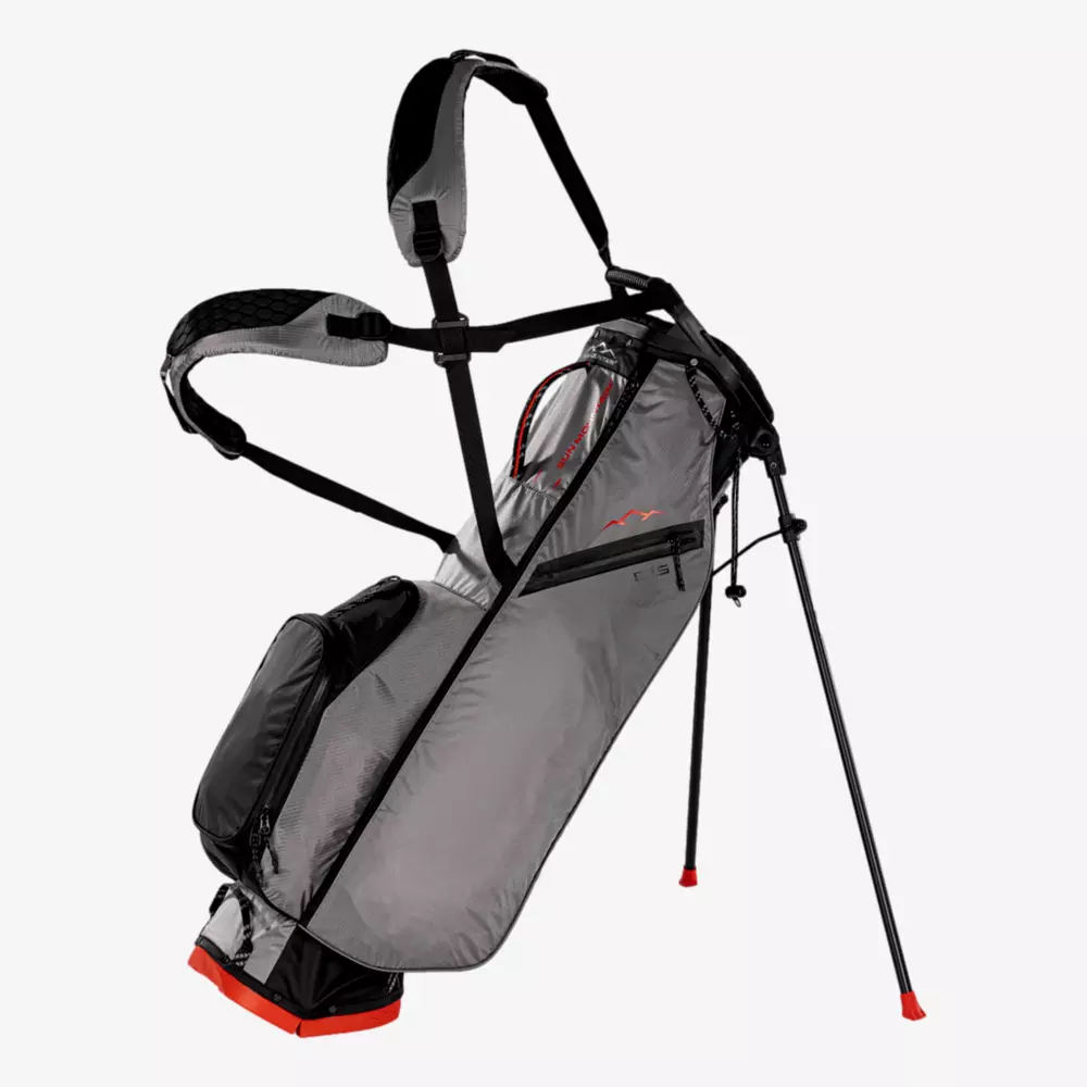 A lightweight gray golf bag with black and red accents stands upright on its two extended legs, featuring multiple pockets and padded dual shoulder straps&mdash;an excellent contender among the best golf bags 2026 has to offer.