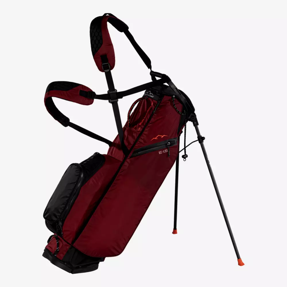 A maroon and black golf stand bag&mdash;one of the best golf bags 2026&mdash;features dual shoulder straps, several zippered pockets, and two extended legs, displayed upright on a white background.