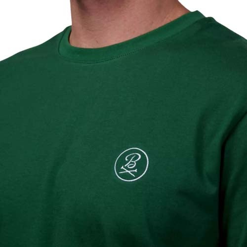 A person wearing a green crew-neck shirt with a small white circular logo and the letter B on the left chest, channeling one of the best looks from The First Major.
