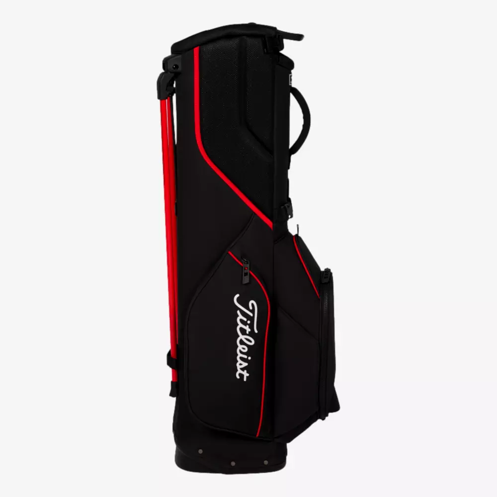 A black Titleist golf bag with red accents and white logo, featuring multiple pockets and a handle on top, stands upright against a plain white background&mdash;an example of the best golf bags 2026 can offer.