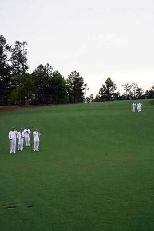 Several caddies survey the grounds of Augusta National during the Masters.