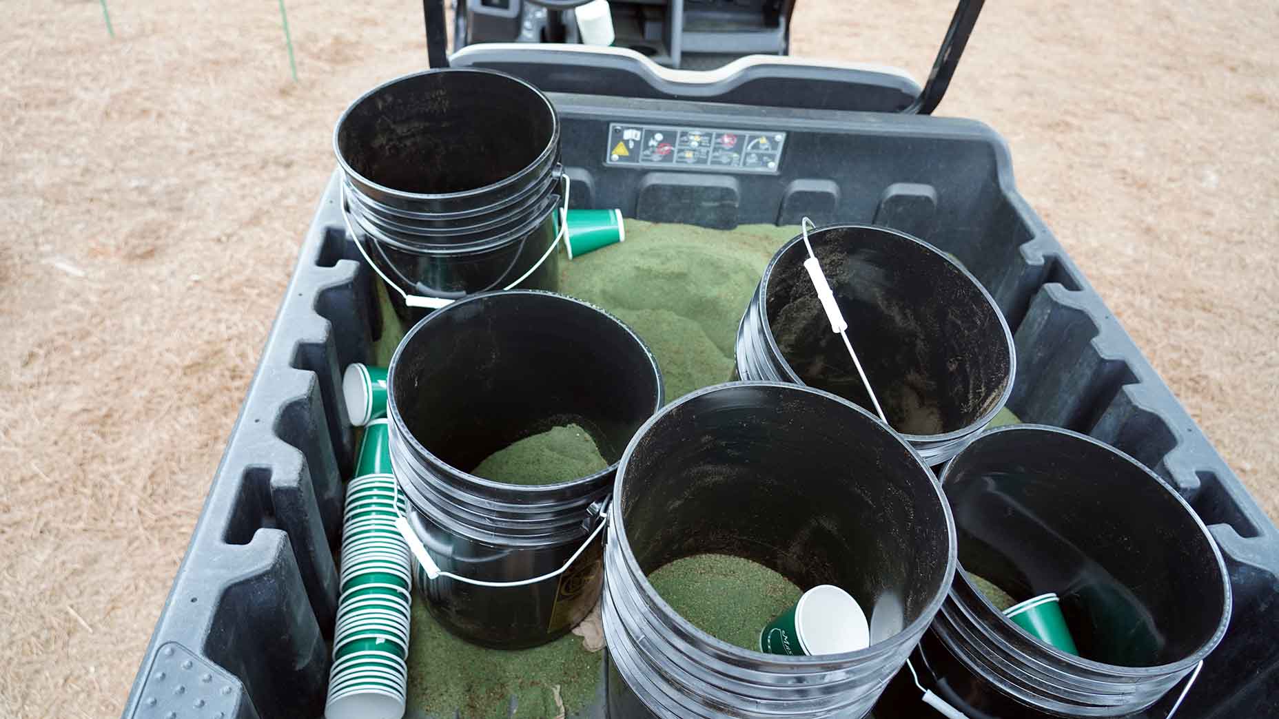 Black buckets filled with green fertilizer sand used at Augusta National during the Masters.