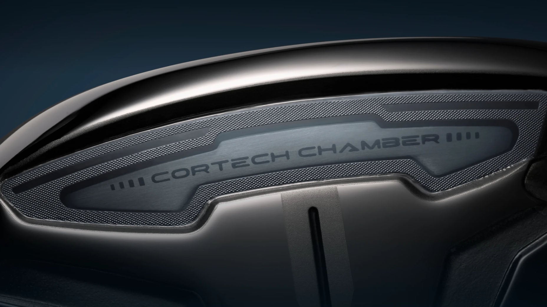 Close-up of a dark metallic golf club head featuring the text Cortech Chamber engraved on a silver section, highlighted against a dark background.