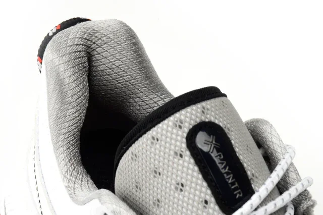 Close-up of the heel and tongue of a white and gray sneaker with PAMNIR branding, featuring textured gray padding and white laces&mdash;designed with inspiration from the best golf shoes 2026, showcased against a clean white background.