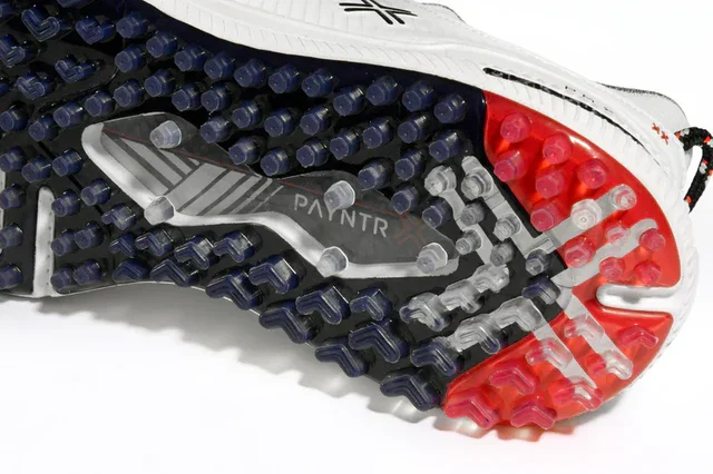 Close-up of the sole of a sports shoe, showing a mix of clear, black, and red rubber studs. The sole features the word PANTR and a textured pattern for grip&mdash;ideal traction found in some of the best golf shoes 2026 has to offer.