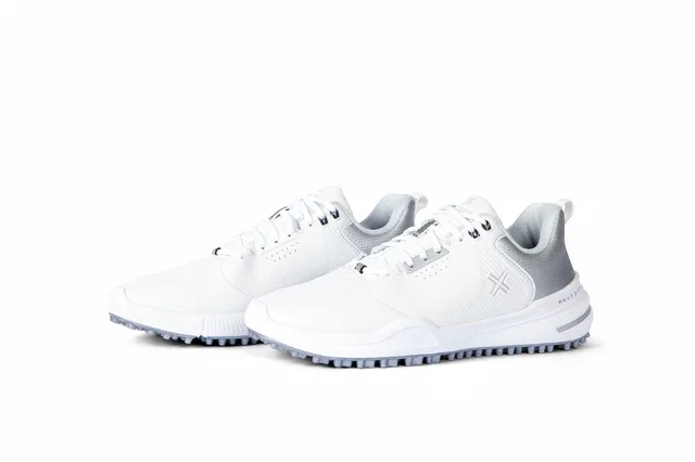 A pair of white athletic sneakers with gray accents&mdash;potentially among the best golf shoes 2026&mdash;featuring textured soles and a subtle logo on the side, displayed on a white background.