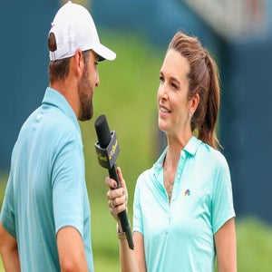 A female reporter in a turquoise NBC Golf shirt interviews a man in a similar blue shirt and white cap outdoors, holding a microphone with a golf course in the background.