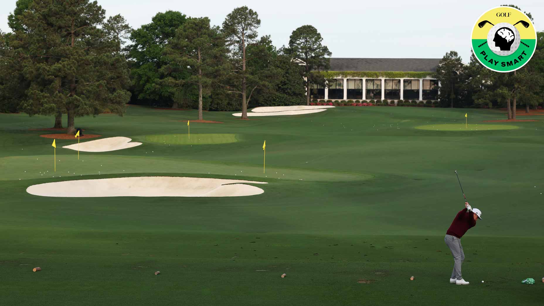 A golfer swings on a lush green golf course with sand bunkers and yellow flags, surrounded by trees. A large clubhouse is visible in the background, and a circular Play Smart! golf logo is in the top right corner.