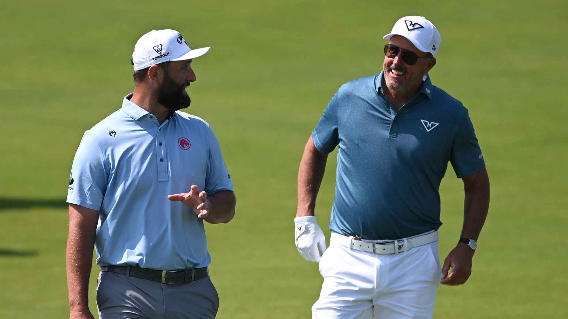 Jon Rahm and Phil Mickelson walk together.