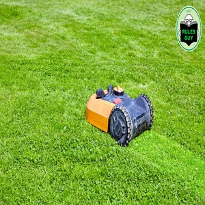 A small robotic lawn mower with orange and black casing moves across a well-manicured green lawn. A circular Golf Rules Guy logo appears in the top right corner.