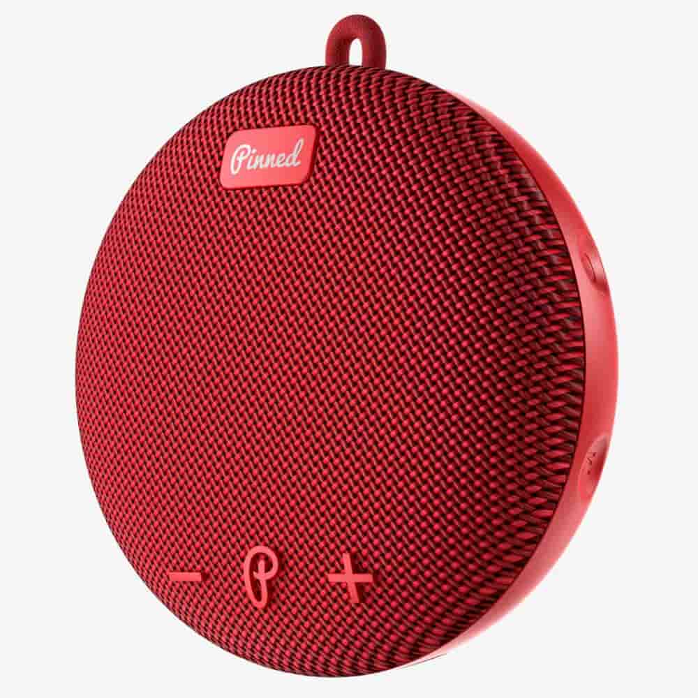 A round, red portable Bluetooth speaker with a fabric front, volume control buttons, and a small loop at the top for hanging—one of the best deals under $50.