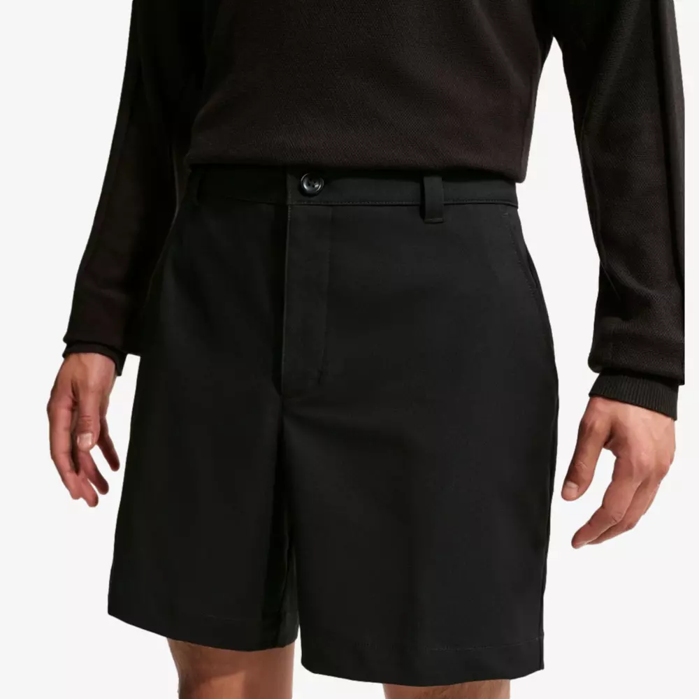 A person wearing a long-sleeve black shirt and black knee-length shorts stands with their arms relaxed at their sides, shown from chest to mid-thigh against a plain background&mdash;perfect attire for browsing the best golf travel bags.