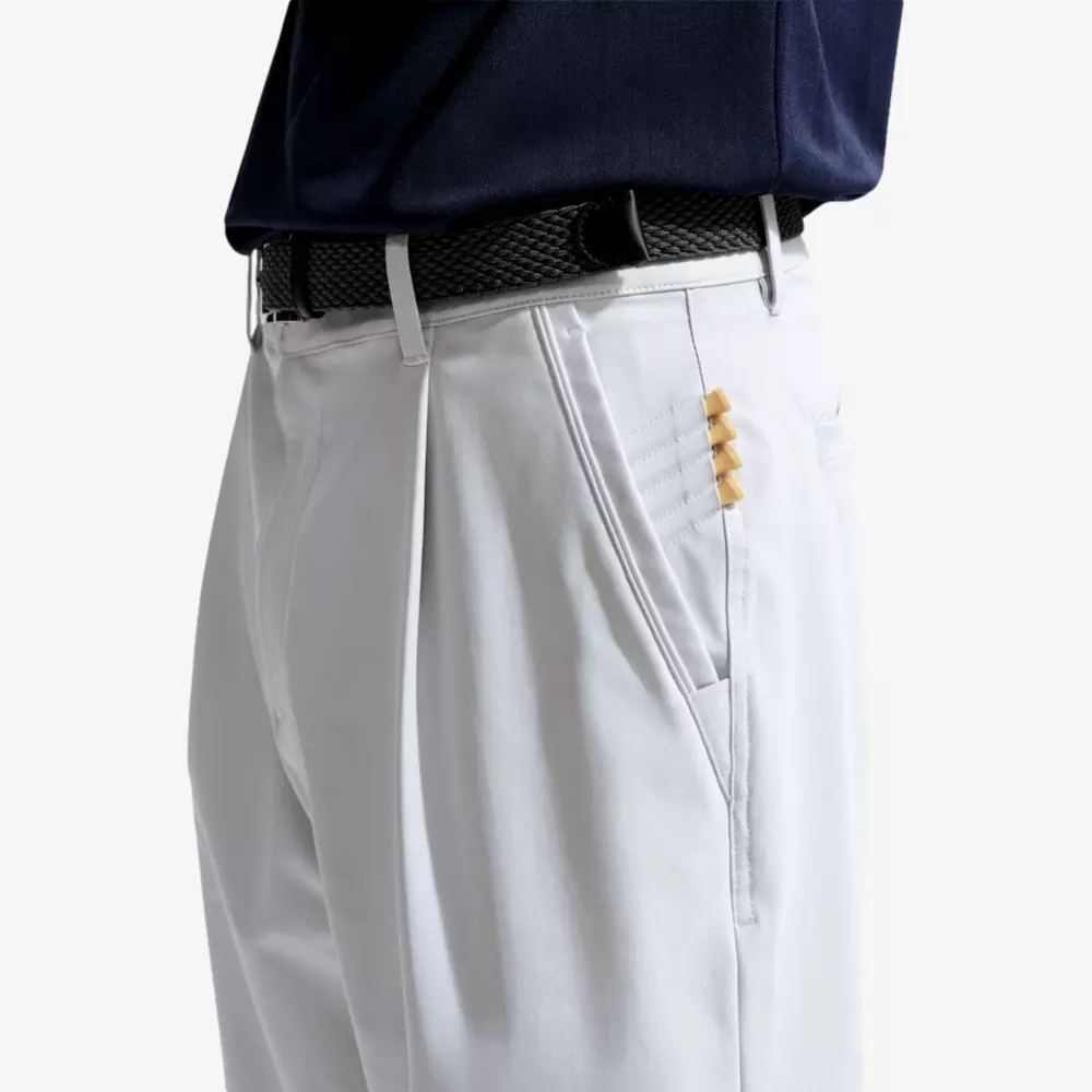 A person wearing white pants with a black belt and a navy shirt, probably ready to go to a lesson. Five little girls peek out from the right pocket—perfect for those who pack the best golf travel bags. Only the lower body is visible.