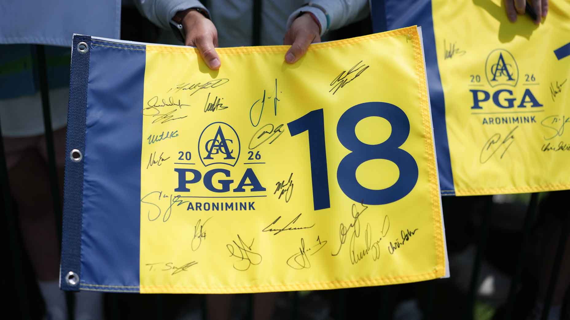 2026 PGA Championship Sunday TV coverage: Fan watches PGA and holds yellow flag at Aronimink.