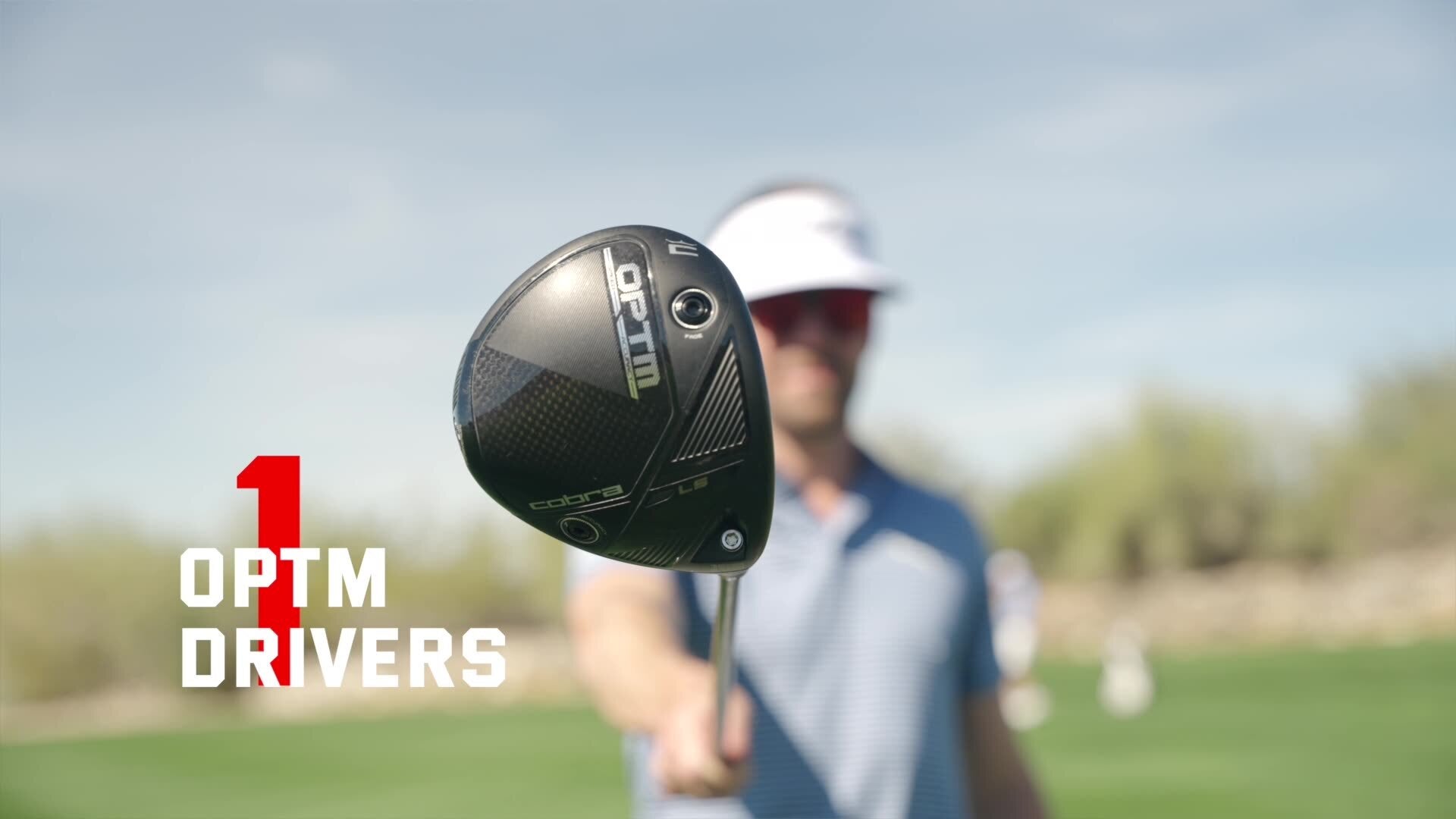 A golfer, possibly Drew Stoltz, stands outdoors holding a Cobra OPTM driver toward the camera, with the text 1 OPTM DRIVERS in bold white and red letters on the left. The golf course background highlights accuracy and precision.