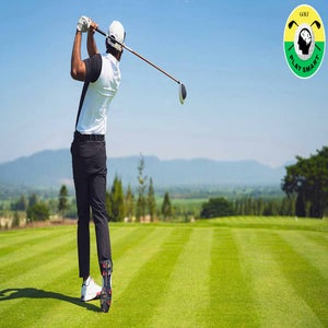 golfer in black pants and white shirt swings golf club on golf course with ocean in the distance