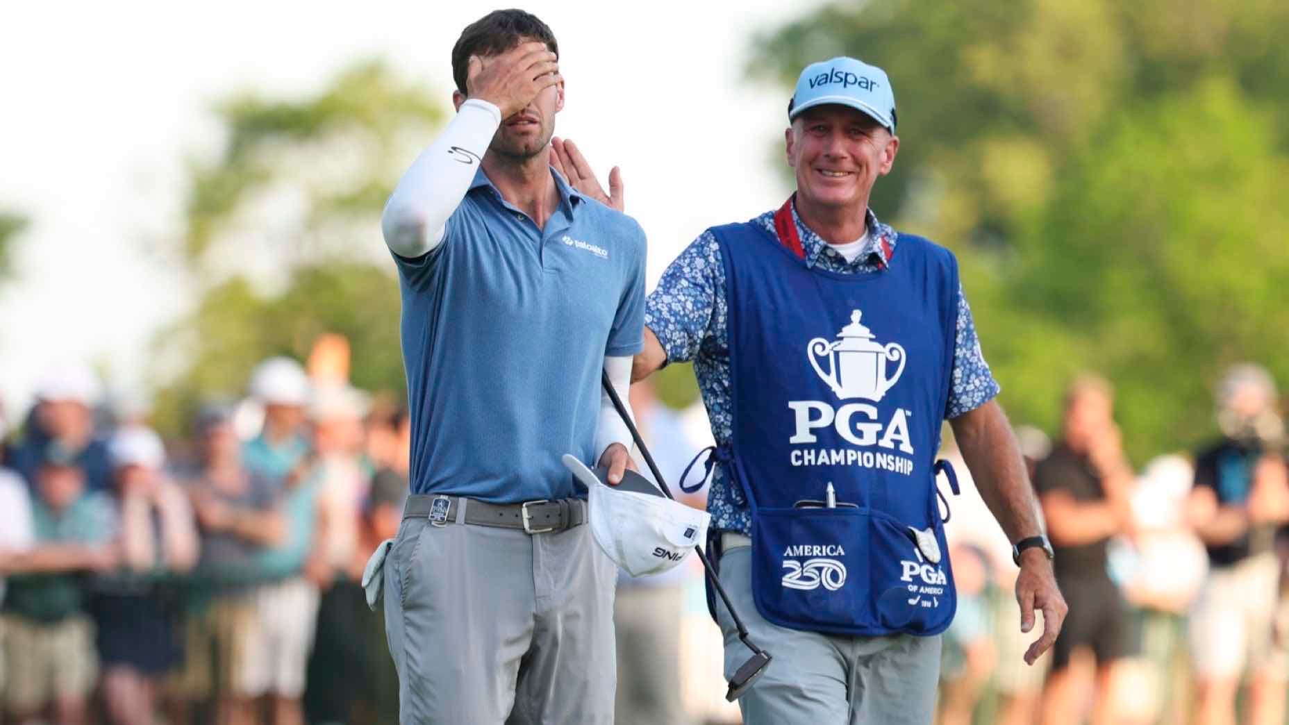 Alex Smalley covers his eyes in apparent disbelief or frustration after missing the Alex Smalley $1 million putt, while his smiling caddie in a PGA Championship vest stands by. A crowd watches in the blurred background.