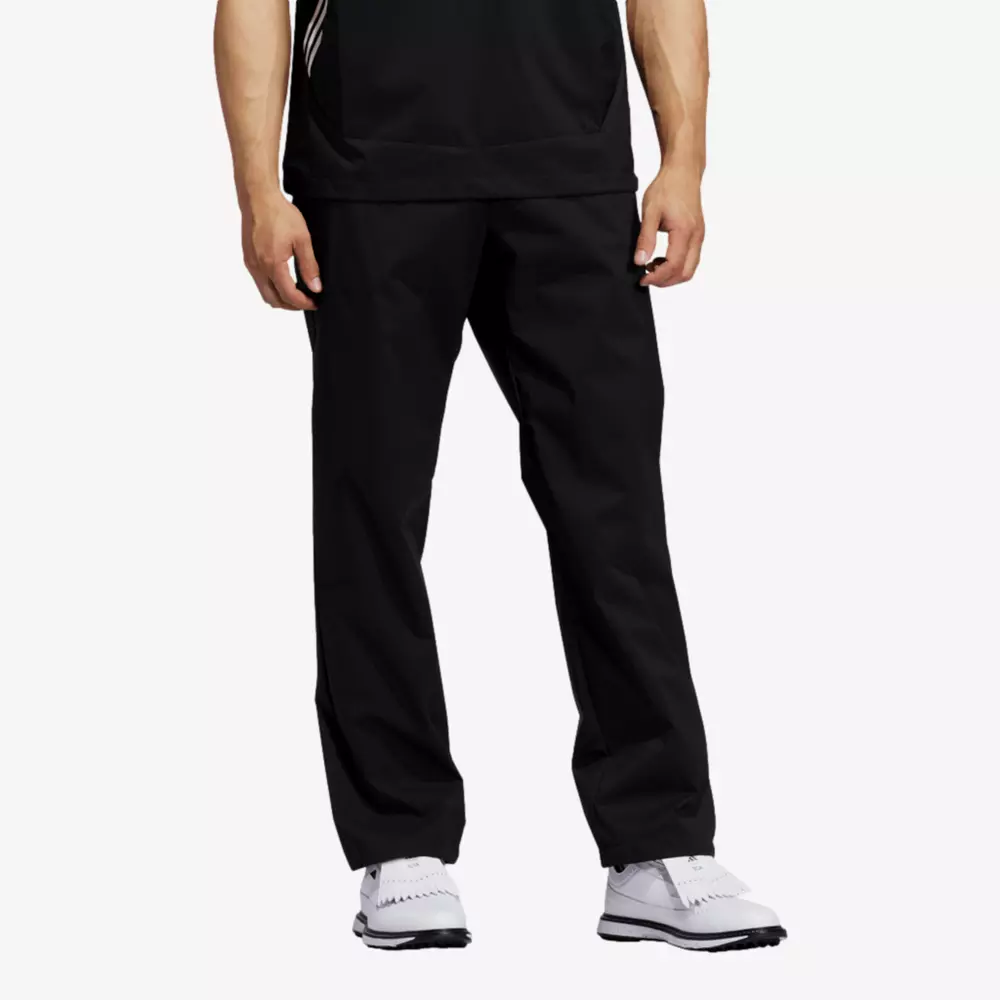 A person wearing black athletic pants, a black shirt, and white sneakers stands against a plain white background—the perfect outfit to browse 6 golf deals worth buying right now. The image focuses on the lower half of the body.