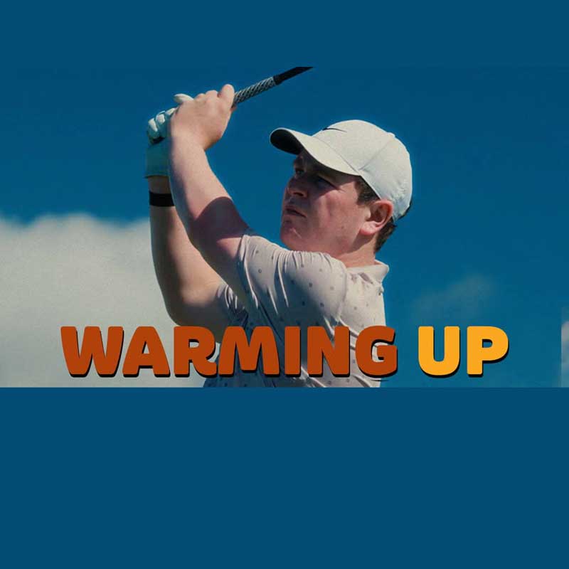 Robert MacIntyre wearing a white cap and shirt swings a club outdoors on the golf course. The words WARMING UP in bold orange and yellow letters appear across the image.