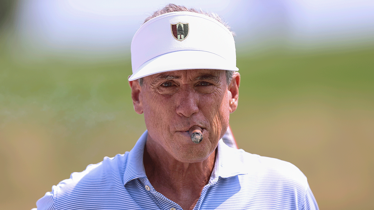 Sporting two Pine Valley Golf Club logos, Mike McCoy enjoys a cigar at the 17th hole tee during the first round of stroke play of the 2026 U.S. Amateur